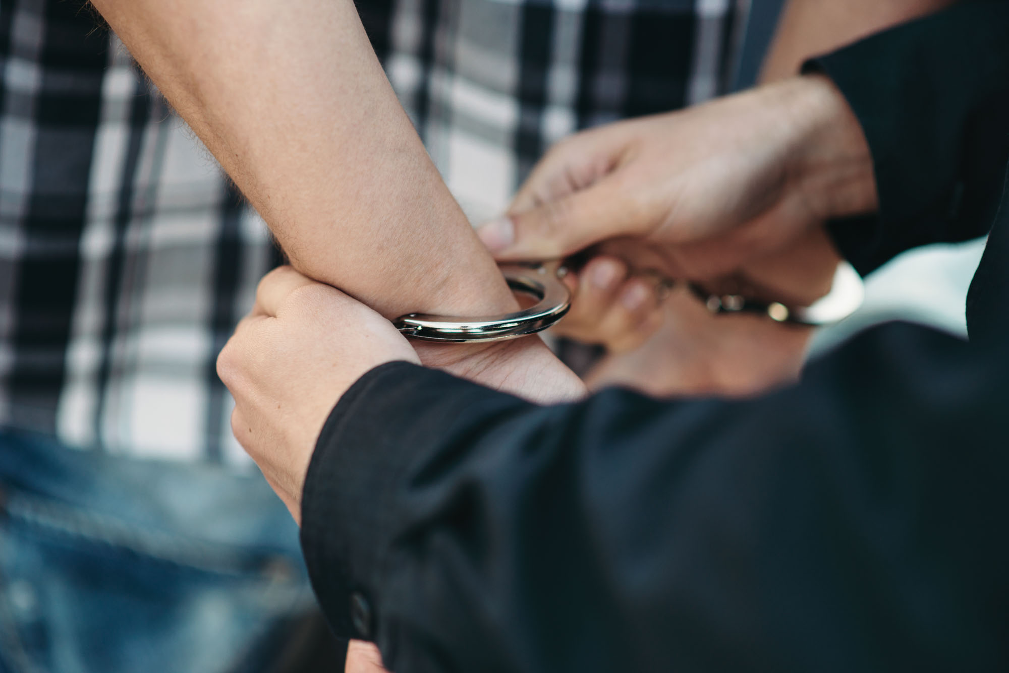 Police officer puts handcuffs on a car thief, policeman arrests the driver violator on road. Cop at the work. Law protection concept, professional safety control Police officer puts handcuffs on a car thief