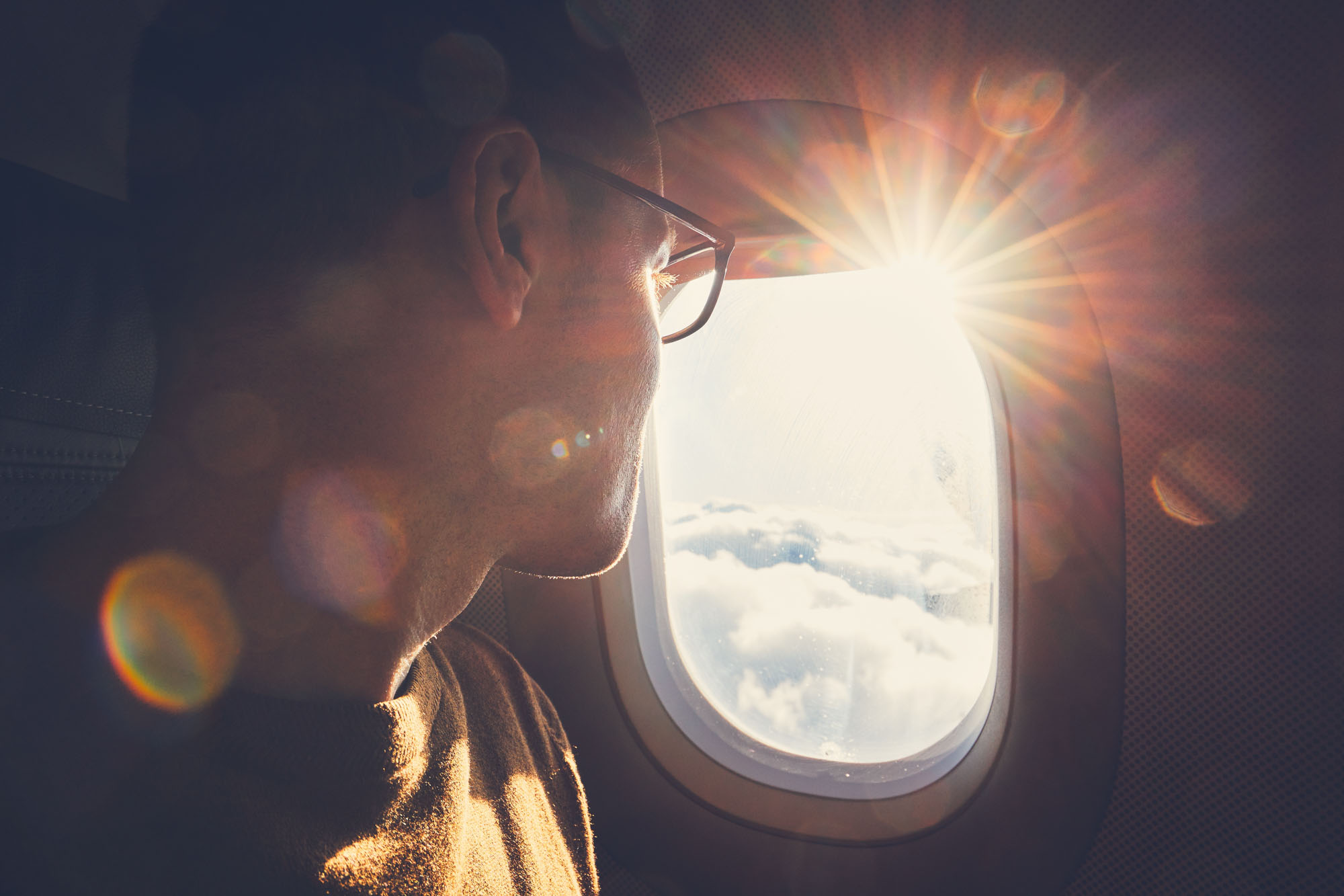 Young man looking out through window of the airplane during beautiful sunrise. Young man looking out through window of the airplane during beautiful sunrise.